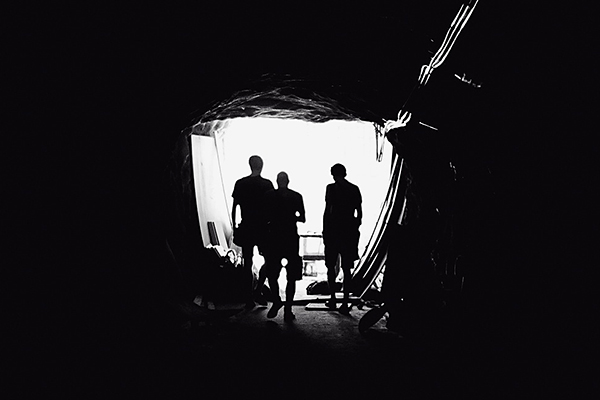 people silhouetted in tunnel entrance