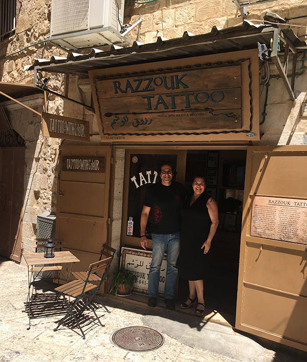 Two people standing outside Razzouk Tattoo shop in Jerusalem