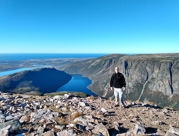 Joseph Pagano standing in front of the view from Gros Morne