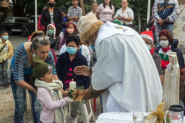 Priest Alfredo Infante blesses a young girl holding a candle
