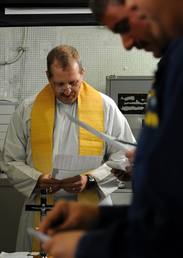 a Navy chaplain conducts prayer on a ship