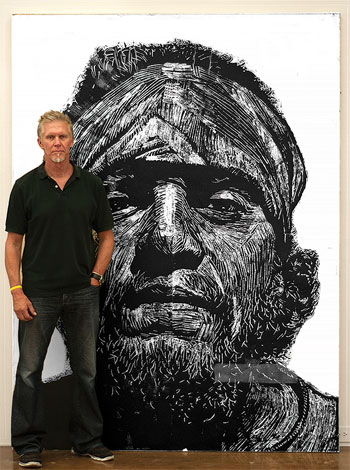 Neil Shigley standing by one of his large portraits of homeless people.