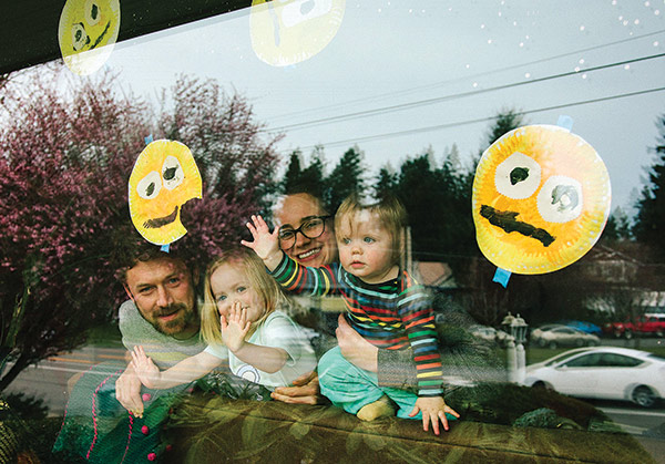 a father and mother and two daughters, photographed at their living room window