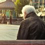 old man sitting on a bench near a subway station