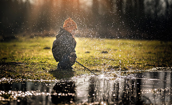 a kid splashing water with a stick