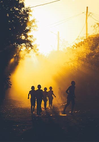 silhouettes of a group of children running on a forest path