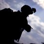 A soldier on duty with a heavy backpack in early dawn light.