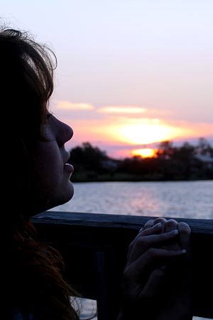 Girl looking out a window at the sunset