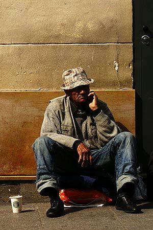 A homeless man sitting on a street corner.