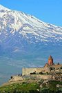 A photograph of Khor Virap monastery with a large snow-covered mountain in the background.