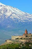 A photograph of Khor Virap monastery with a large snow-covered mountain in the background.