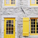 grey stone building with yellow shutters