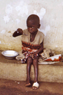 A young girl eats from a tin bowl during a famine crisis in Nigeria.