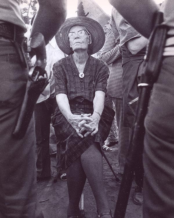 Dorothy Day, seated in front of two police officers