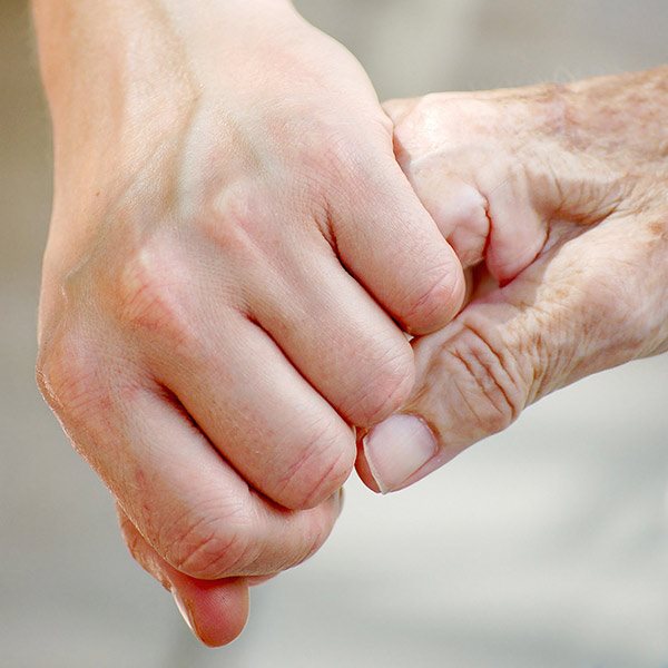 a young hand holding an elderly hand