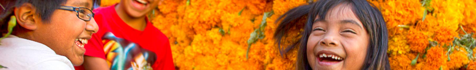 Laughing mexican children with a background of orange marigolds
