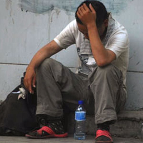 A tired man sitting on the pavement