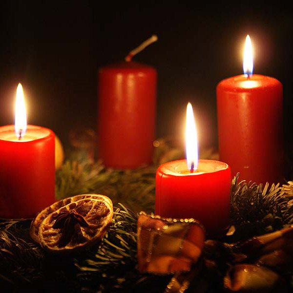 four red candles on a wreath of green pine and ribbons