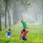 two boys jumping to hit a soccer ball in a forest