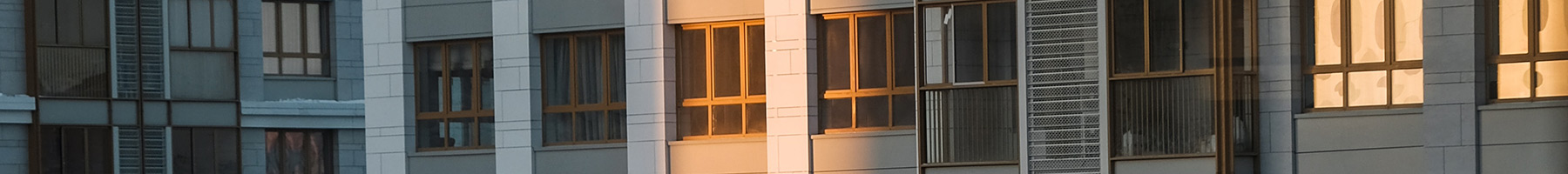 early morning sunlight shining on the windows of city apartments