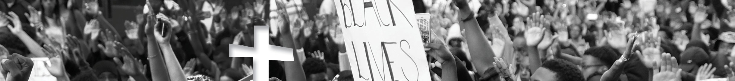 A photo of a Black Lives Matter rally with a cross cut out of white paper. 