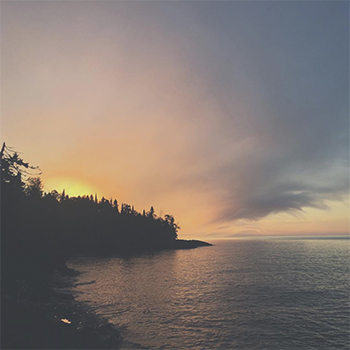 sunset over a dark shoreline