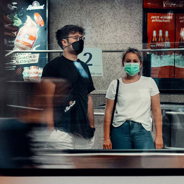 man and woman wearing masks seen through a train window