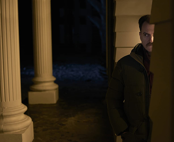 a man peering around the corner of a house