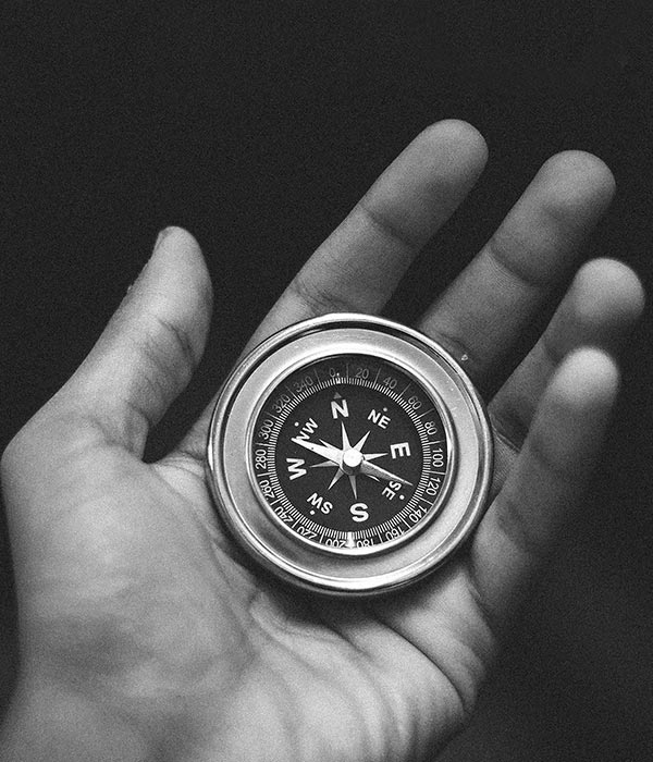 black and white photo of a hand holding a compass