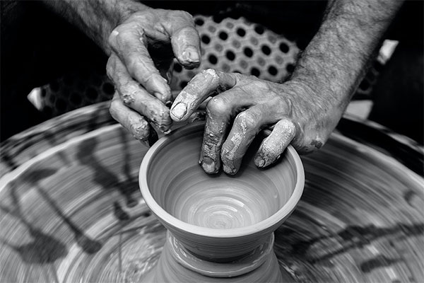 black and white photo of someones hands forming a bowl on a potters wheel