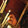 photo of an older woman in a headscarf lighting white taper candles