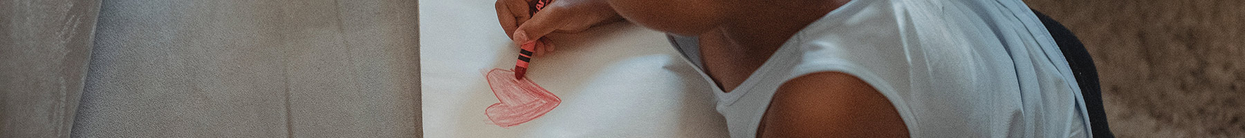 a little girl coloring a heart on a piece of paper