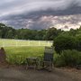 photo of a rocking chair on a front porch with a white fenced field in the background