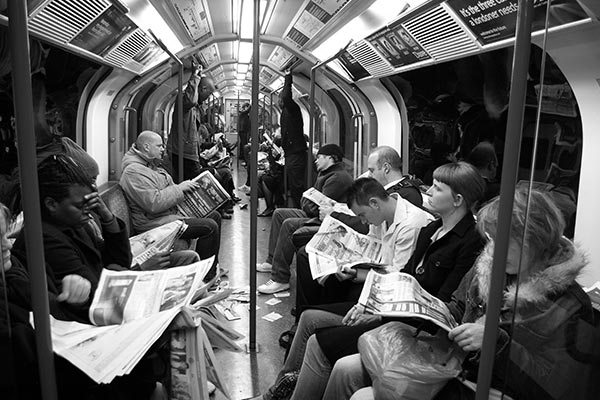 full train of people reading newspapers