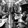 full train of people reading newspapers