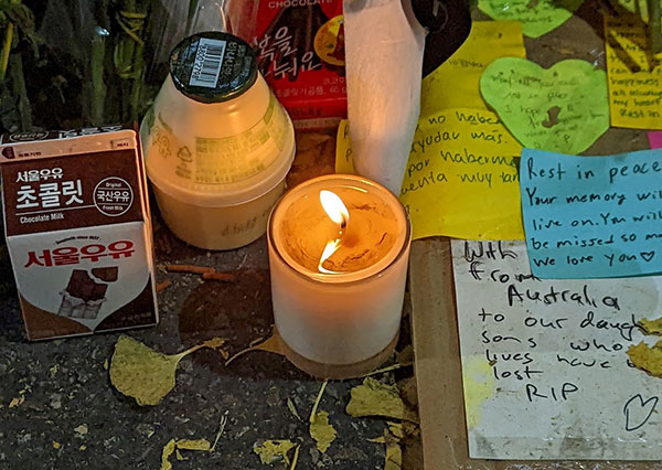 candle burning in a jar among notes and flower petals
