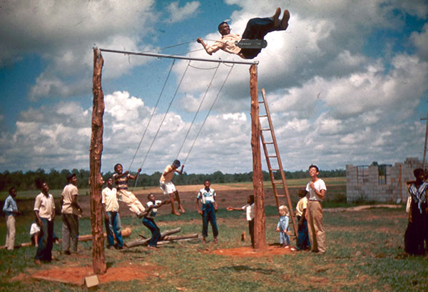 kids and adults at Koinonia playing on a swing set, 1940s or 50s