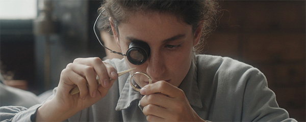 Still from the film Unrest, a young woman fixing a clock
