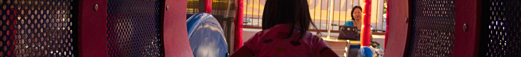 child playing in fast food restaurant playground with her mom in the background