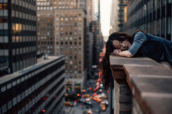 Woman resting on her arms on a balcony overlooking a city