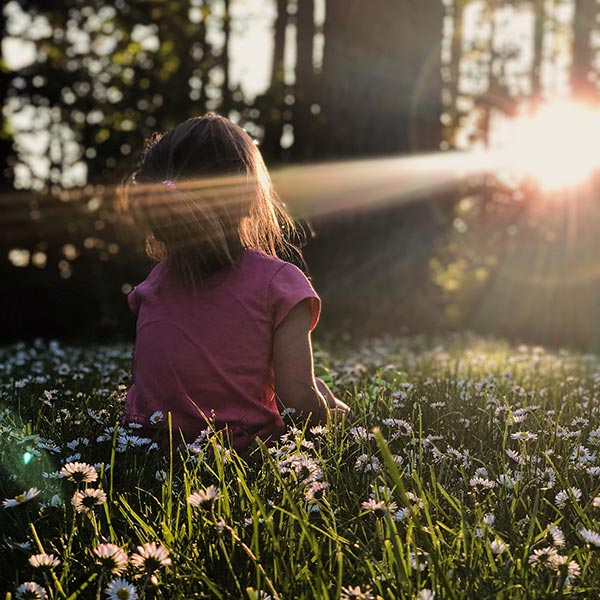 little girl in a sunny field of daisies