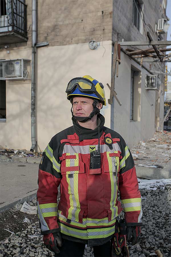 man in a red firefighters uniform among rubble