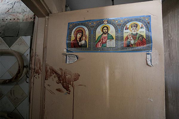 icons on a wall with blood smeared below