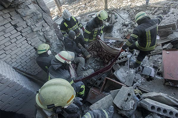 several men in firefighter uniforms carrying a body in a tarp out of rubble