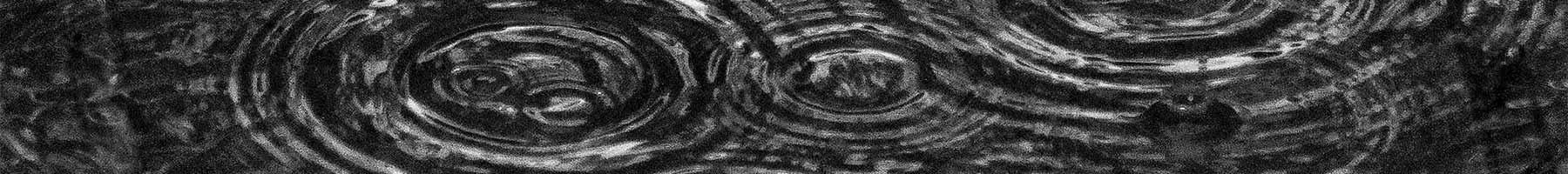 black and white photo of rain ripples on pavement