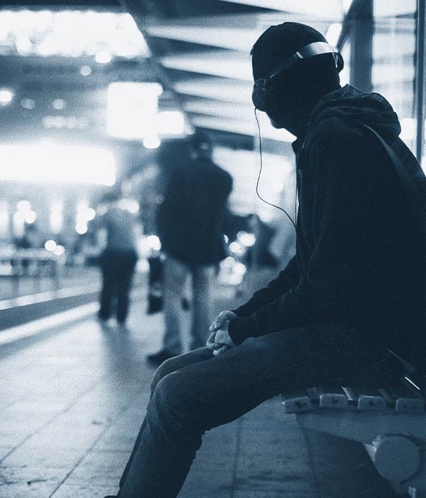photo of a person with headphones sitting in a train station