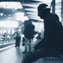 photo of a person with headphones sitting in a train station