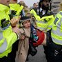 young man protesting for Extinction Rebellion being carried by London police officers in bright yellow jackets