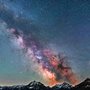 a galaxy above snow covered mountains