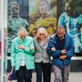 Three elderly people linking arms while walking